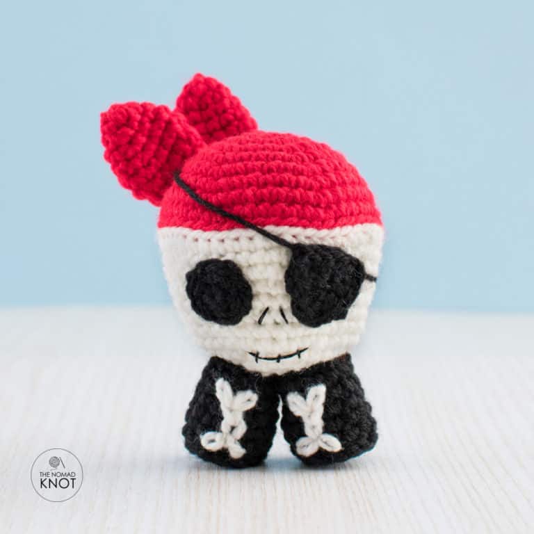 Skull Pirate Amigurumi on top of a white table and a blue background - Free Halloween Pattern