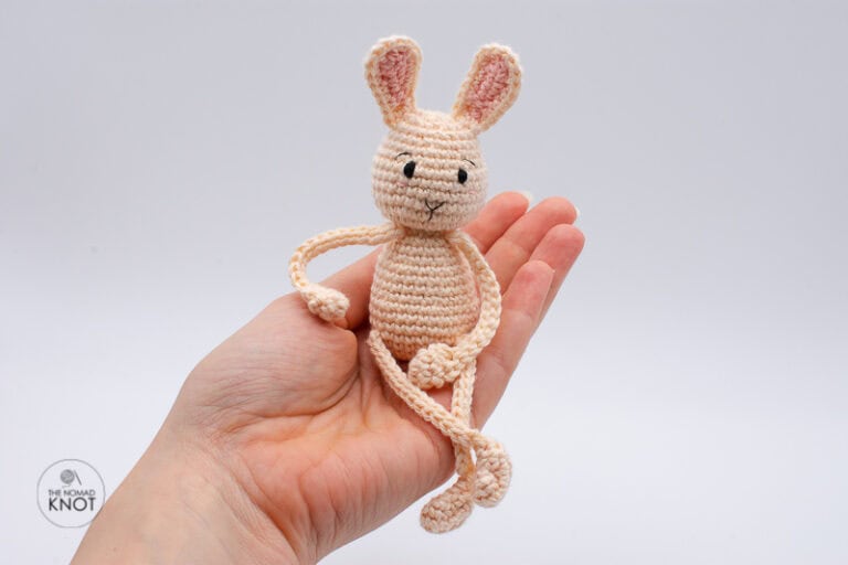 Crochet Posable bunny free pattern sitting and posing on top of a hand