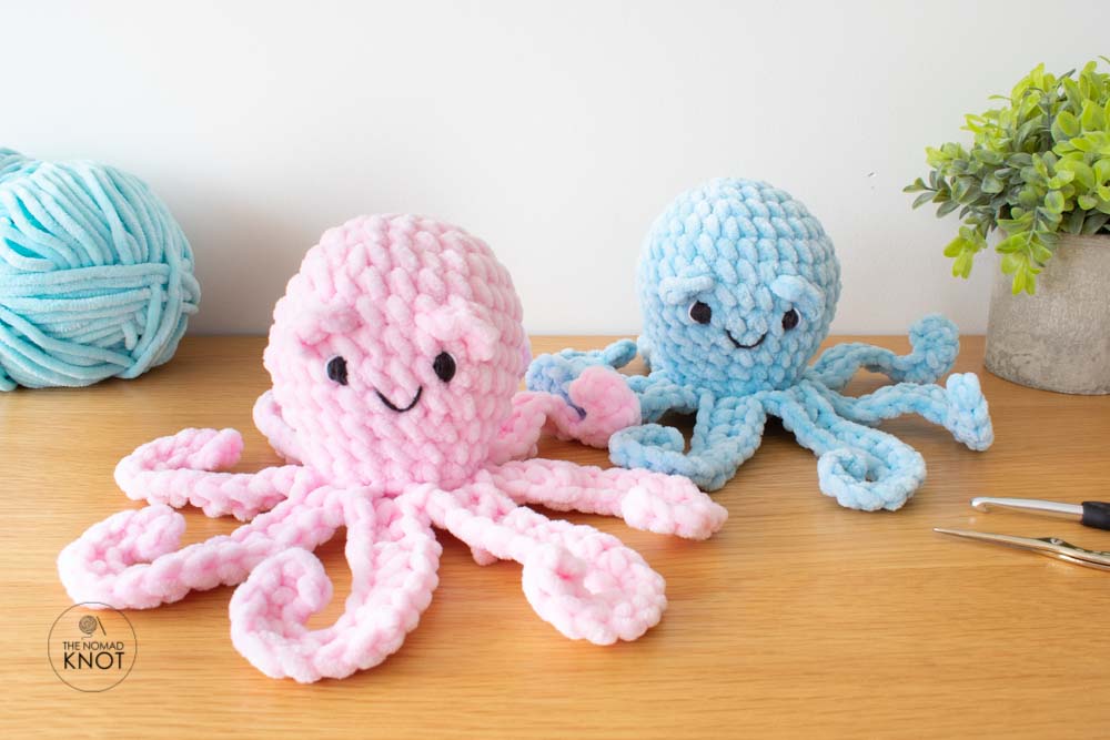 image feature two crochet octopus one in blue and the other one pink, on top of a shelf with a skein of yarn in one side and a small plant pot in the other