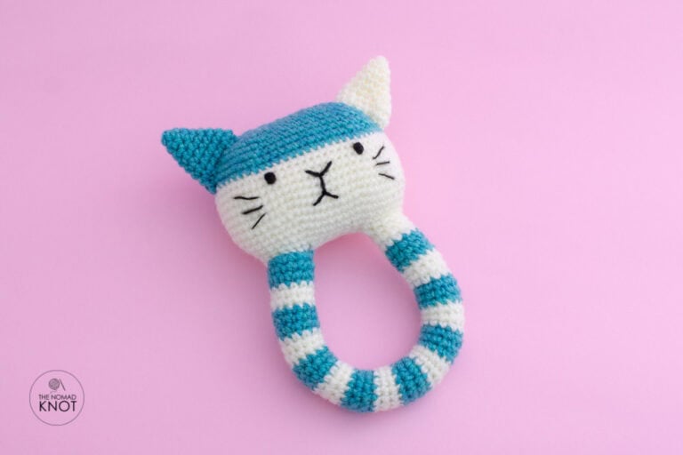 crochet cat rattle free pattern amigurumi for newborns on top of a pink background