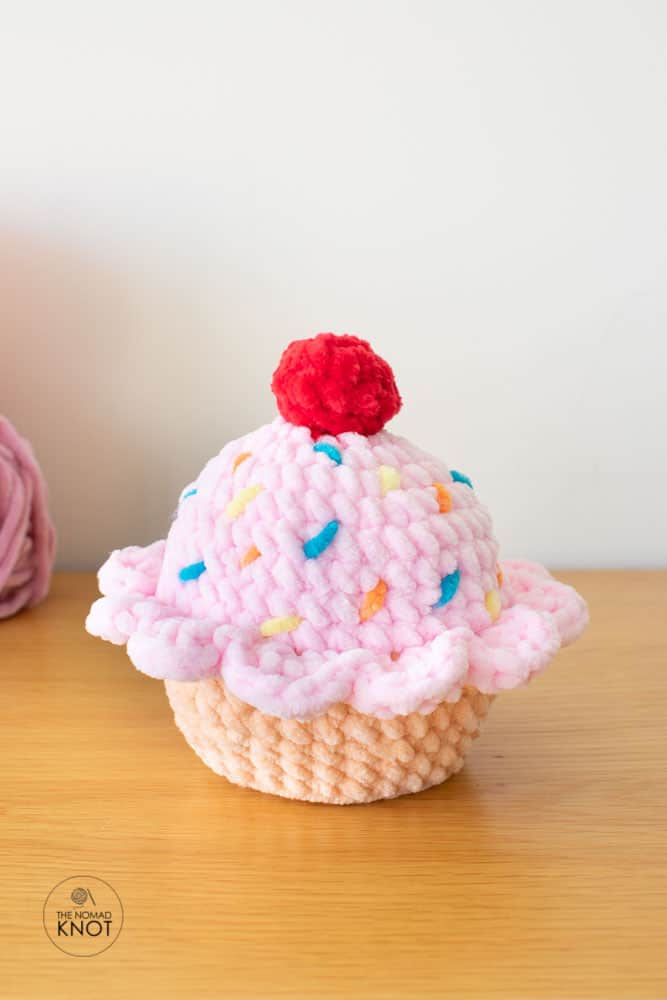 Crochet plush cupcake made with velvet yarn displayed on a shelf