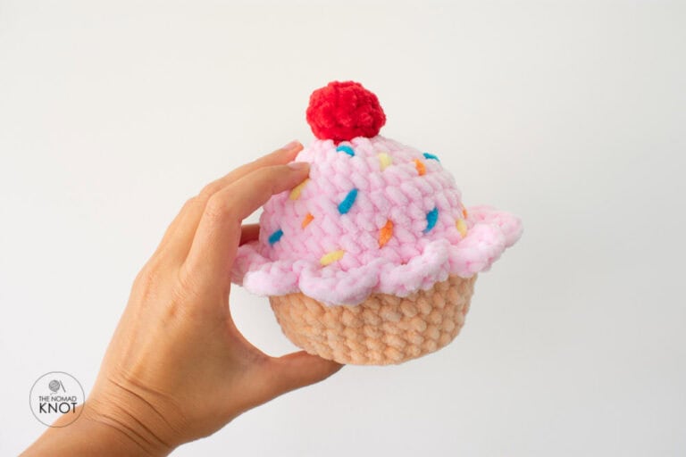 No-sew crochet cupcake amigurumi held in hands on white background