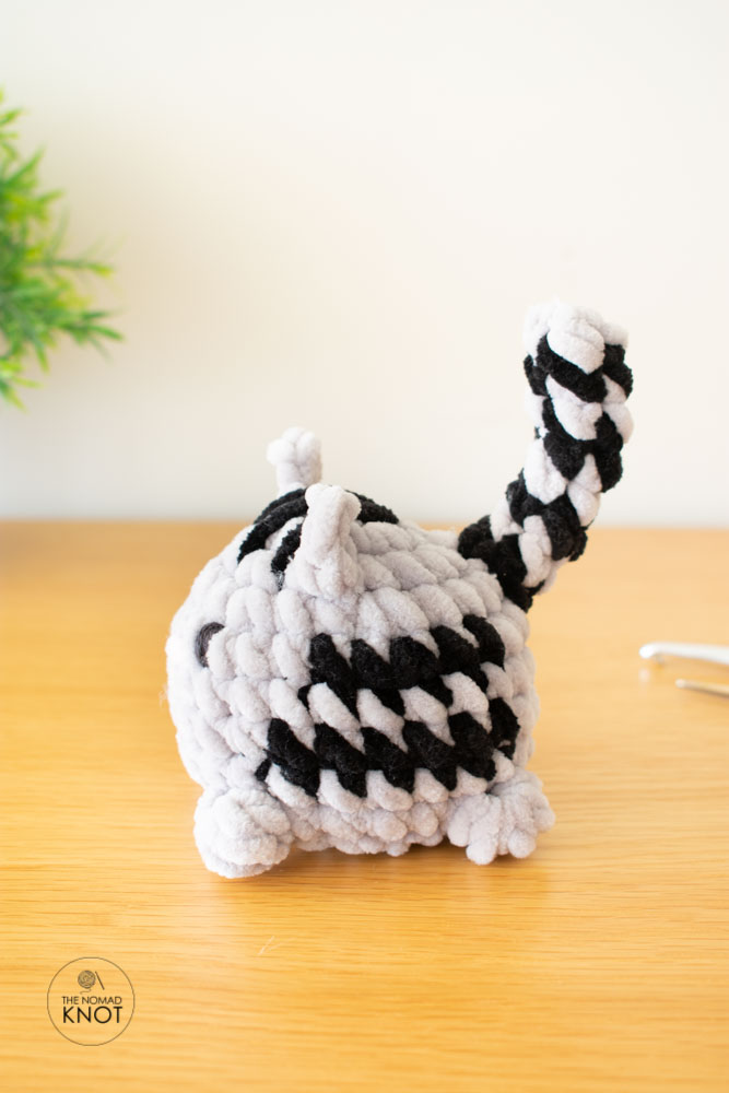 no-sew crochet cat gray tabby free pattern on top of a wooden table with a plant on the background