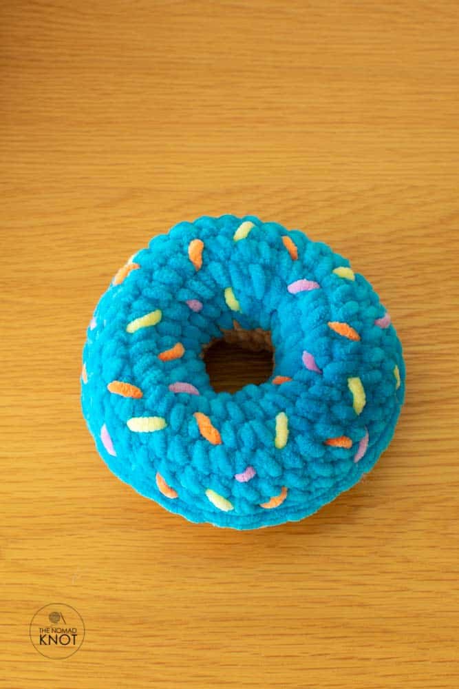 Crochet plush donut on top of a wooden table shot from above