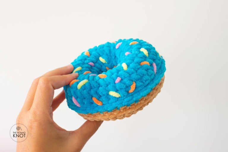 crochet plush donut free pattern held by one hand on a white background