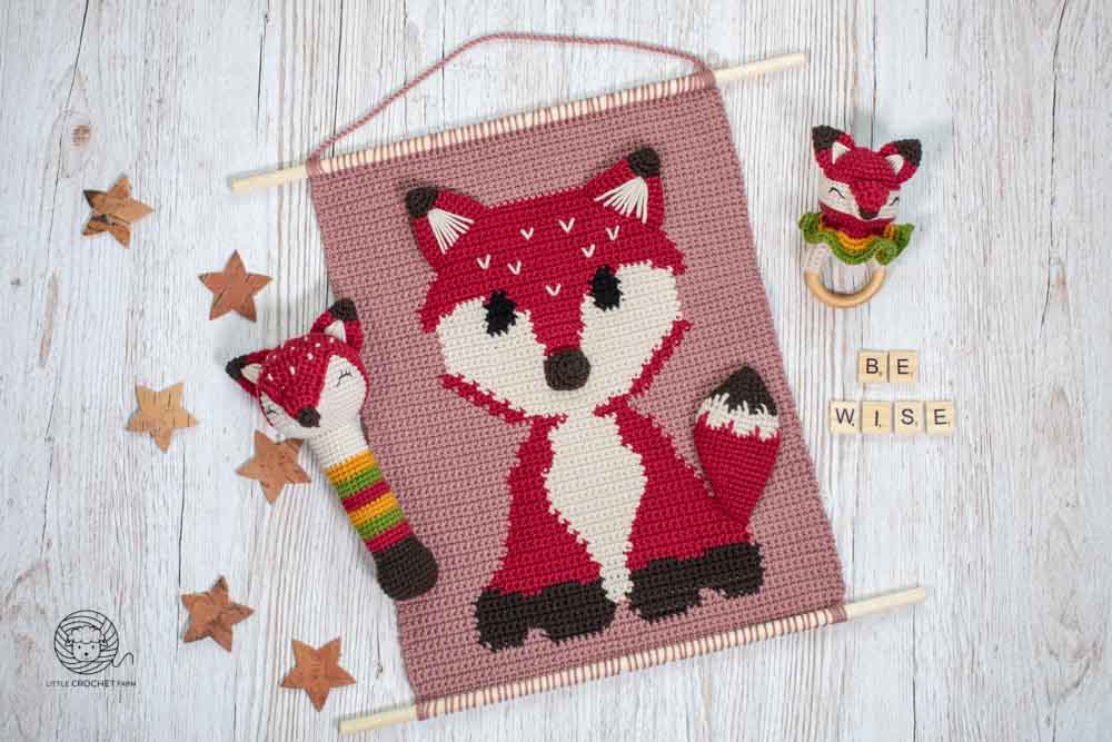 crochet wall hanging free pattern Baby Fox, a fox rattle and wooden teething ring on top of a wooden table with wooden stars